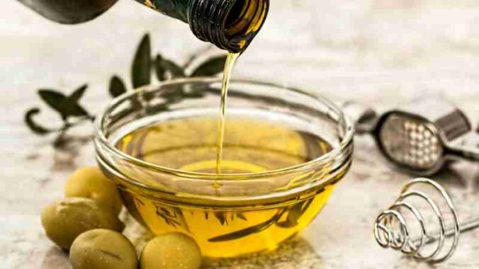 Close-up of olive oil being poured into a glass bowl surrounded by fresh olives and kitchen tools., tags: di culturale - pexel